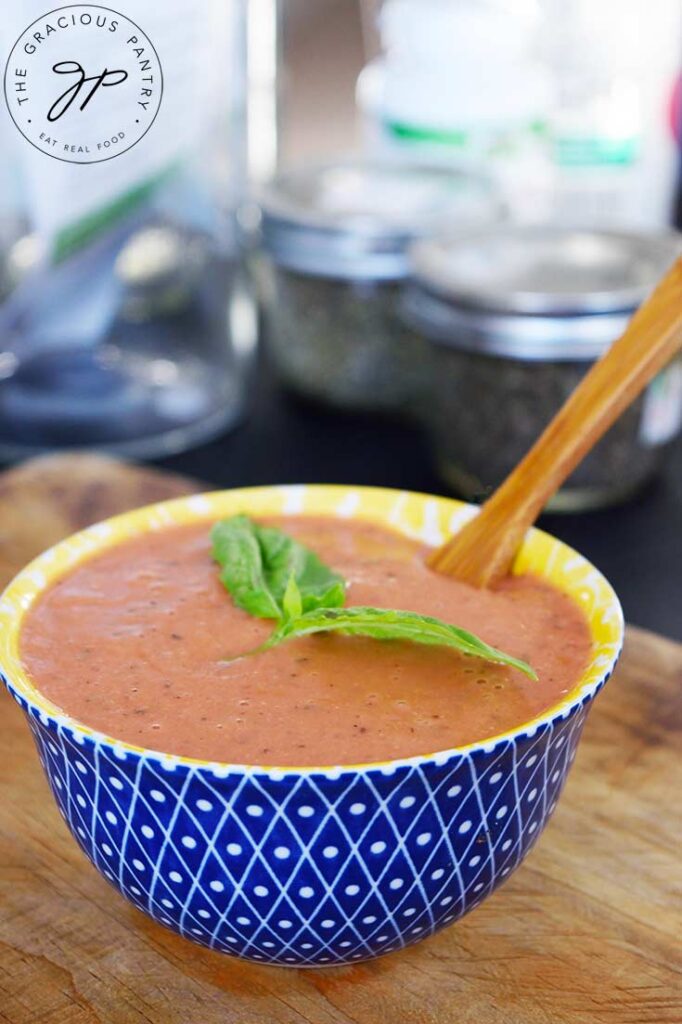 A side view of a blue and yellow bowl filled with Healthy Tomato Soup.