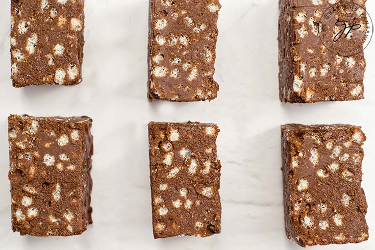 Six Homemade Crunch Bars lined up on white parchment paper.