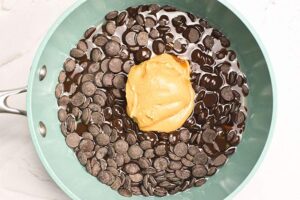 Peanut butter added to melting chocolate chips in a skillet.