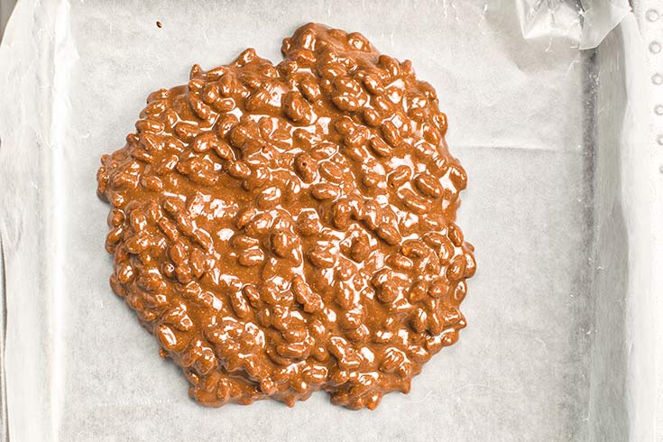 Homemade Crunch Bars batter poured into a parchment-lined baking pan.