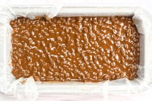 Homemade Crunch Bars batter spread over a parchment-lined baking pan.