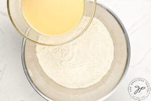 Adding wet ingredients to dry ingredients in a mixing bowl.