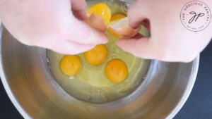 Cracking eggs into a mixing bowl.