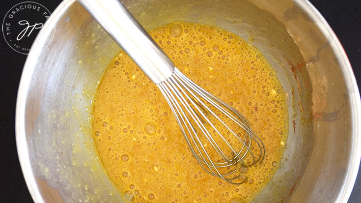 Whisked egg mixture sitting in a mixing bowl with a whisk.