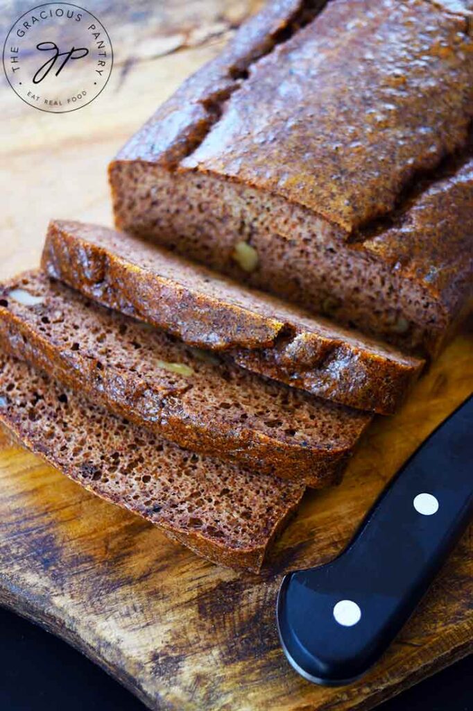 A loaf of Pecan Butter Bread sitting on a cutting board with three slices cut from the loaf.