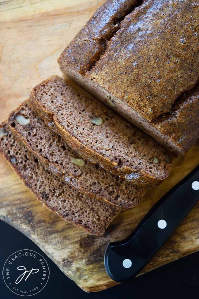 An overhead view looking down onto a loaf of pecan butter bread that has three slices cut and laying in front of it.