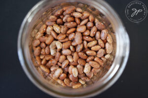 Dry pinto beans in a glass jar viewed from overhead.