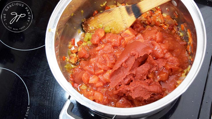 Diced tomatoes, green chilis and tomato paste added to a pot of sautéd vegetables.