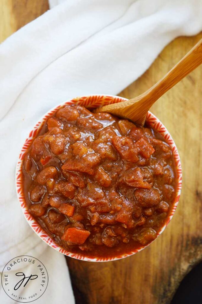 A small bowl with Ranch Style Beans and a wooden spoon resting in the bowl.