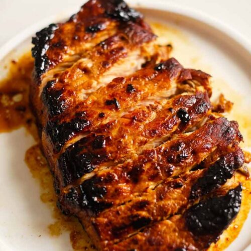 A single, cooked, balsamic pork chop, sliced and served on a white plate.