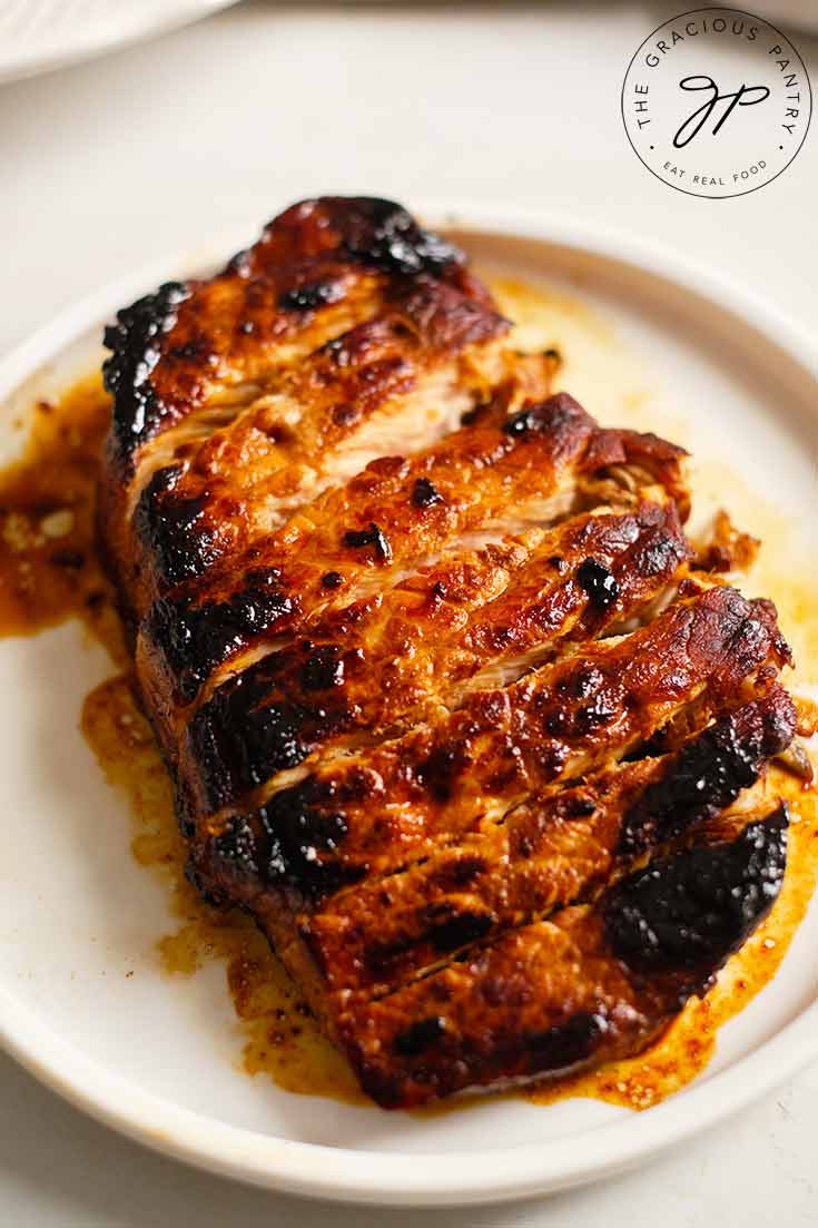 A single, cooked, balsamic pork chop, sliced and served on a white plate.