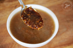 A spoon holds up a spoonful of Chinese Garlic Sauce.