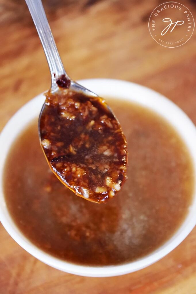 A front view of a spoon holding up a spoonful of Chinese Garlic Sauce.