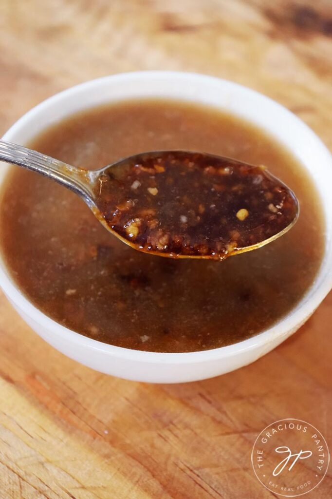 A side view of a spoon holding up a spoonful of Chinese Garlic Sauce.