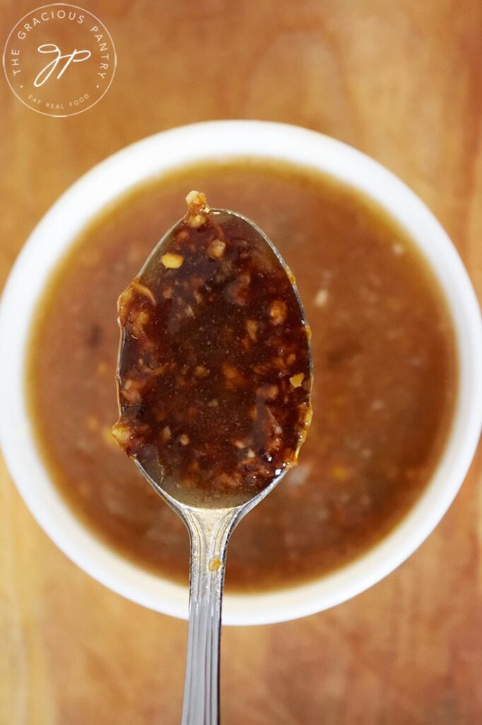 An overhead view of a spoon holding up a spoonful of Chinese Garlic Sauce.