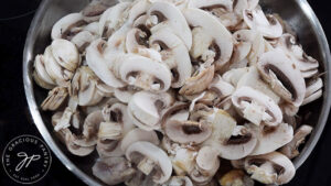 Mushrooms in a skillet over chicken.