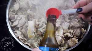 Adding soy sauce and balsamic vinegar to mushrooms and chicken in a skillet.
