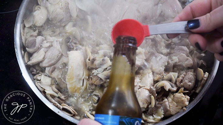 Adding soy sauce and balsamic vinegar to mushrooms and chicken in a skillet.