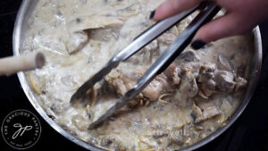 Stirring a skillet filled with this Creamy Garlic Mushroom Chicken Recipe