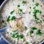 A spoon lifts some Creamy Garlic Mushroom Chicken out of a skillet.