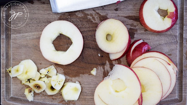 Cored apple slices laying on a cutting board.