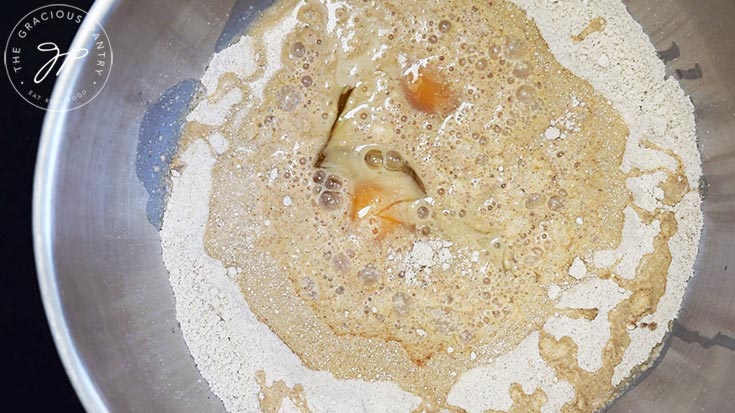 Eggs and milk added to a flour mixture in a mixing bowl.