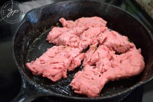 Raw ground turkey in a cast iron skillet.