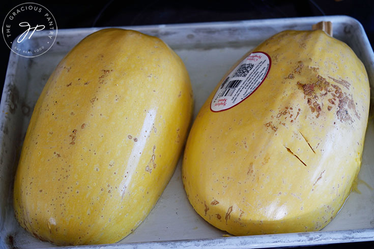 Two spaghetti squash halves turned cut side down on a baking pan.