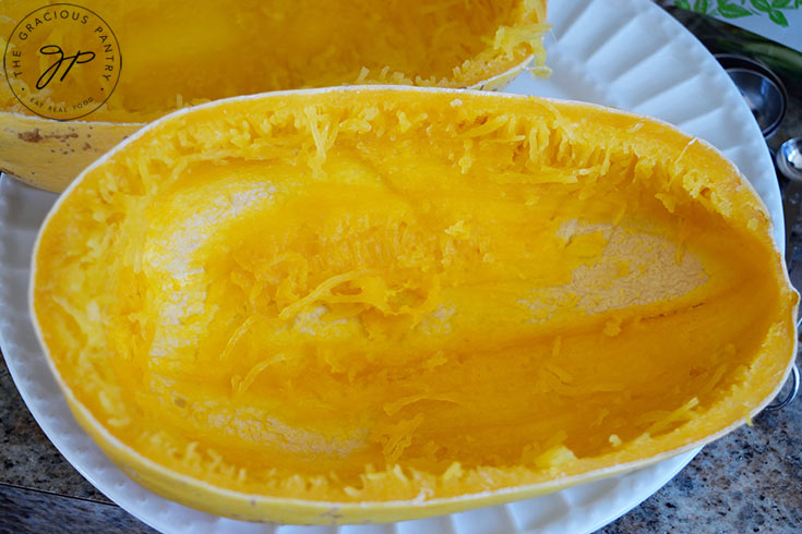 Two empty spaghetti squash halves rest on a plate.