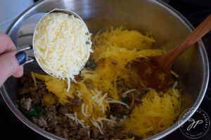 Adding grated mozzarella to the Italian Spaghetti Squash Boats filling.