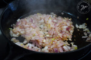 Onions sautéing in a cast iron skillet.