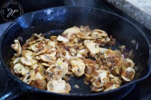 Onions and mushrooms cooked until golden brown in a cast iron skillet.