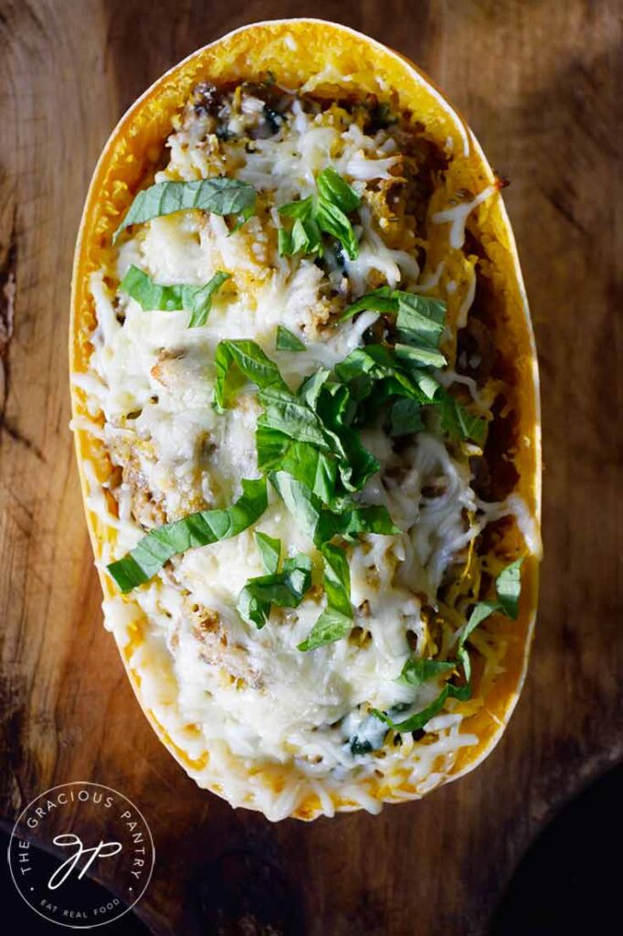 An overhead view of one of the Italian Spaghetti Squash Boats sitting on a cutting board topped with fresh, shopped basil.