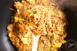 A spoon lifts a portion of Healthy Pork Fried Rice out of a wok.