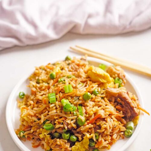 A white plate sits on a white surface filled with Healthy Pork Fried Rice.