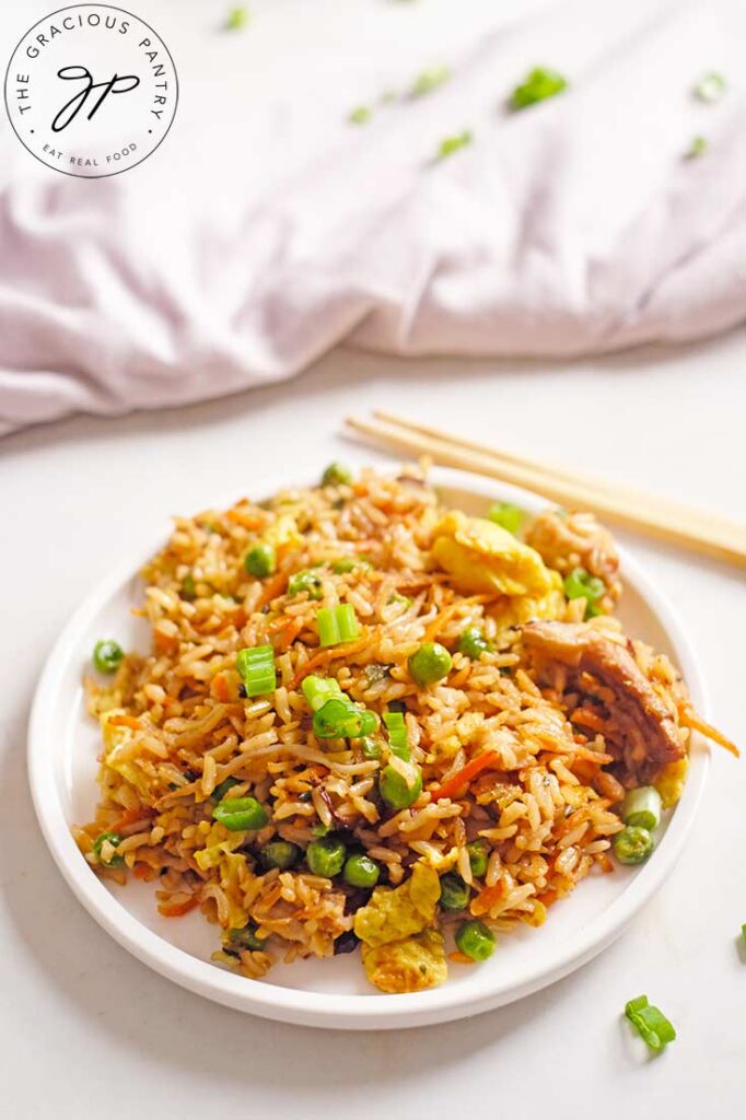 A white plate sits on a white surface filled with Healthy Pork Fried Rice.