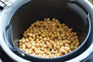 Cooked chickpeas sitting in an air fryer basket.