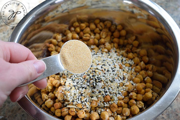 Adding garlic powder to a bowl or roasted chickpeas.