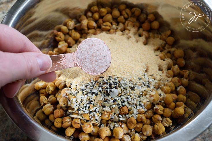 Adding salt to a bowl of roasted chickpeas.