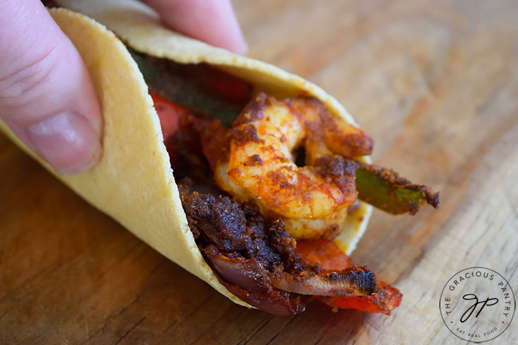 A femail hand holds a Sheet Pan Shrimp Fajita closed.