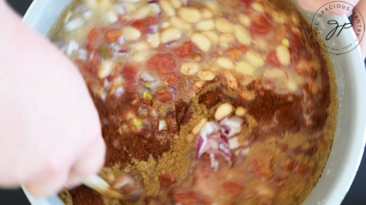 Stirring together all the Crockpot White Chicken Chili Recipe ingredients in a crock.