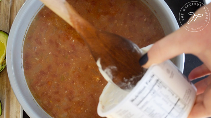 Adding yogurt to Crockpot White Chicken Chili after cooking.