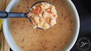 A ladle scoops up some Crockpot White Chicken Chili from a crock.