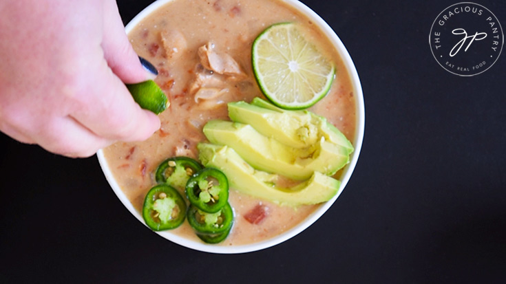 Squeezing fresh lime juice over a bowl of Crockpot White Chicken Chili.