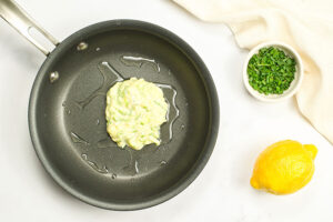 A bit of zucchini fritter batter just added to a hot pan with oil.