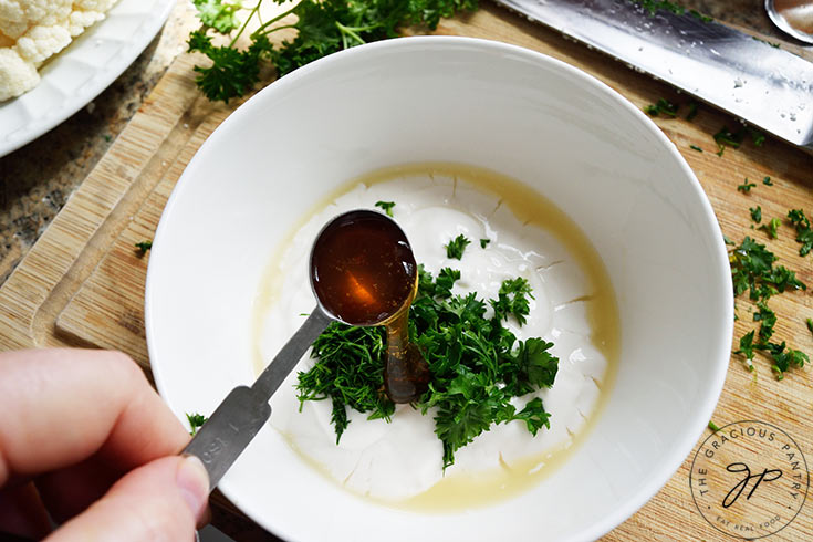 Adding honey to yogurt in a mixing bowl.