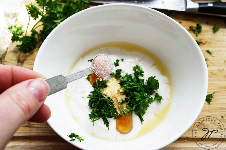 Adding salt to yogurt in a mixing bowl.