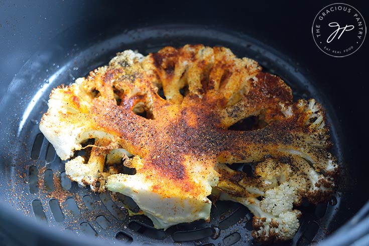 A cooked Air Fryer Cauliflower Steak sitting in an air fryer basket.