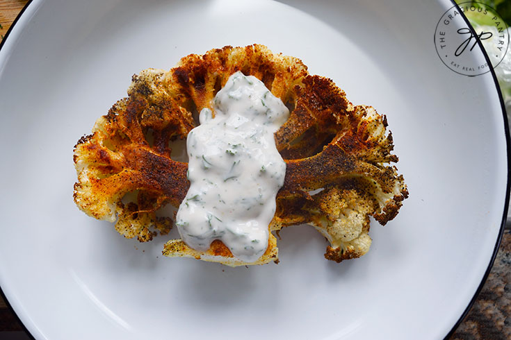 Ladling yogurt sauce over an Air Fryer Cauliflower Steak.