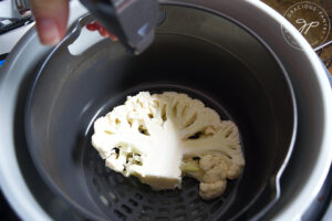 Spriting a cauliflower steak with a bit of oil from an oil sprayer.